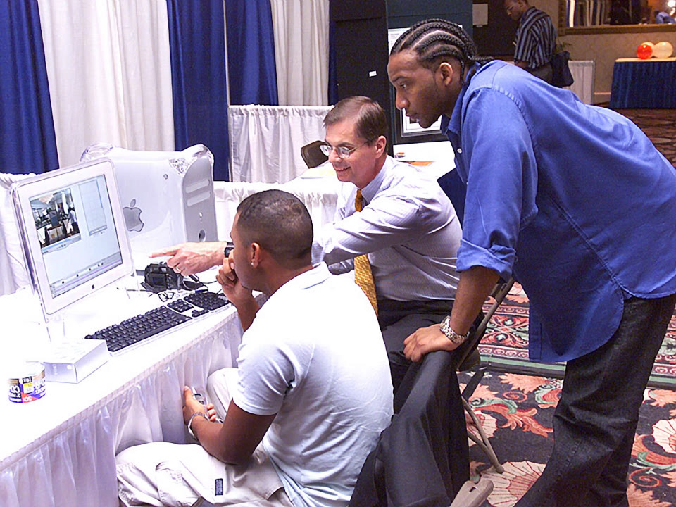 William Miecuna leaning over a computer alongside residents at a Neighborhood Networks technology center