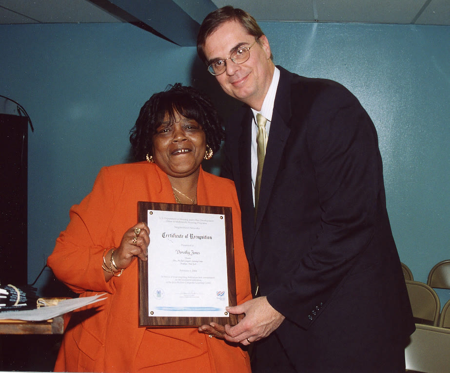 William Miecuna standing arm in arm with a graduate holding her framed certificate of completion